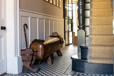 a bench sitting in the middle of a hallway next to a door with an umbrella and boots on it