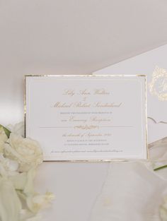 a white and gold wedding card with flowers