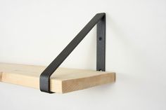 a wooden shelf with black metal brackets on it