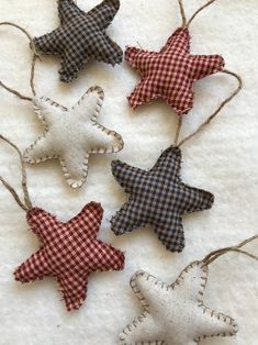 four star ornaments hanging from twine on a white tablecloth with gingham checkered fabric