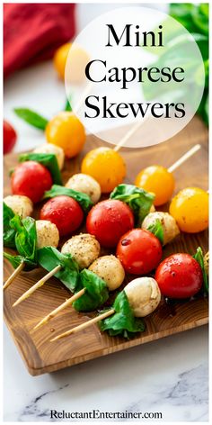 mini caprese skewers on a wooden board with tomatoes and spinach