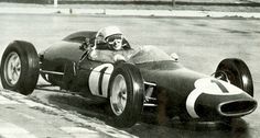 an old black and white photo of a man driving a race car