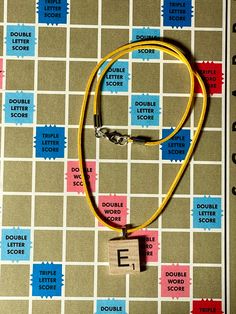 a yellow necklace with the letter e on it is sitting on a table next to a notebook