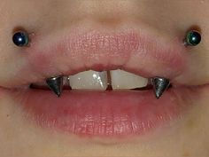 a woman's mouth with two metal spikes on it