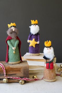 three small figurines made to look like king and queen on top of books