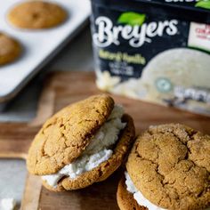 two cookies with ice cream are on a cutting board next to a bag of butter