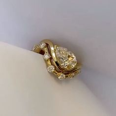 a yellow gold ring with two pear shaped diamonds on it's sides, set against a plain white background