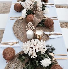 the table is set with white flowers and pine cones