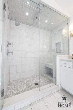 a bathroom with a walk in shower next to a white sink and counter top under lights