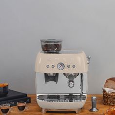 an espresso machine sitting on top of a wooden table next to some bread