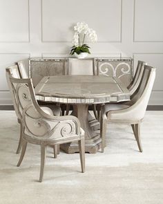 a dining room table with chairs around it and a vase on the table next to it