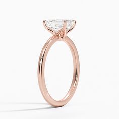 Emerald Cut Petite Elodie Solitaire Engagement Ring - 14K Rose Gold. This elegant solitaire ring features an open basket with claw prongs that cradle the center gem. The petite band adds to the sleek, classic look of the design. 14k Rose Gold Solitaire Jewelry With Round Band, Rose Gold Wedding Ring With Single Diamond, Rose Gold Moissanite Ring With Single Diamond, Rose Gold Solitaire Diamond Ring, Asscher Cut, Rose Gold Asscher Cut Solitaire Diamond Ring, Rose Gold Moissanite Ring With Prong Setting, 14k Rose Gold Solitaire Wedding Ring, Solitaire 14k Rose Gold Round Wedding Ring, 14k Rose Gold Diamond Ring With Prong Setting