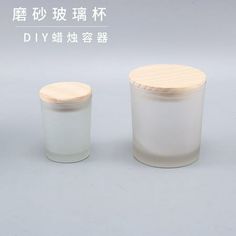 two glass jars with wooden lids on a white surface, one containing an empty jar and the other containing a smaller container