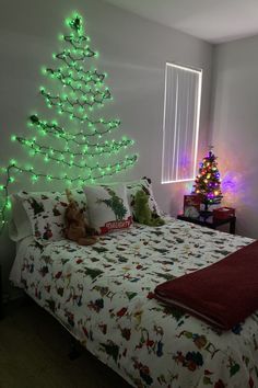 a christmas tree is lit up in the corner of a room with a bed and window