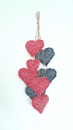 three hearts hanging from strings on a white wall with string attached to them and some red, blue, and black heart shapes