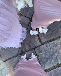 two women in pink dresses and white shoes standing next to each other on the ground