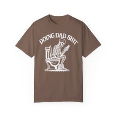 ✨💀 Introducing our "Doing Dad Shit" Skeleton T-Shirt! 💀✨ 🎉 Celebrate Father's Day with a humorous twist by gifting this custom tee featuring a skeleton on a toilet and the phrase, "Doing Dad Shit"! 🎉 💖 Crafted from 100% ring-spun cotton, this garment-dyed t-shirt offers unbeatable softness and comfort, perfect for everyday wear. 💖 😌 The soft-washed fabric adds an extra layer of coziness, making this tee an ideal choice for dads who appreciate both comfort and humor. 😌 💪 With double-needle stitching throughout, this tee is built to last, ensuring durability for all of dad's adventures. 💪 🔄 Say goodbye to bothersome side-seams – our shirt maintains its tubular shape for a sleek and flattering fit. 🔄 🎨 Show your appreciation with this fully customizable design featuring a playful Funny Screen Print T-shirt For Father's Day, Funny Father's Day T-shirt With Screen Print, Father's Day T-shirt With Funny Text In Relaxed Fit, Funny T-shirt For Father's Day Streetwear, Novelty Funny Print T-shirt For Streetwear, Father's Day T-shirt With Funny Print In Relaxed Fit, Father's Day T-shirt With Funny Print, Father's Day Funny Print Short Sleeve T-shirt, Father's Day Cotton T-shirt With Graphic Print