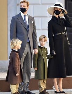 a man, woman and two children wearing face masks while standing in front of a building