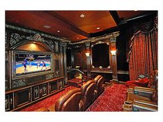 an ornately decorated living room with red carpet and leather furniture, along with a large flat screen tv mounted on the wall