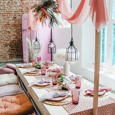 a table set up for a party with pink and gold decorations on the tables, along with hanging birdcages