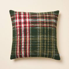 a green and red plaid pillow sitting on top of a white wall