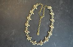 "Much of the Coro jewelry was designed by Gene Verri.  Coro was one of the most prolific jewelry companies in Mid-Century America.  This is a delightful floral deigned necklace with aurora  borealis rhinestone in a goldtone setting.  It measures 17\" long but was most likely worn at the 15\" or 16\" length leaving a one to two inch dangle down the back.  It is very pretty and in excellent condition." Gold Metal Flower Necklace For Wedding, Elegant Metal Flower Necklace For Wedding, Vintage Gold Flower Necklace For Wedding, Vintage Flower Necklaces For Anniversary, Gold Flower-shaped Jeweled Jewelry, Vintage Flower Necklaces For Formal Occasions, Vintage Flower Necklace For Formal Occasions, Flower-shaped Jeweled Wedding Jewelry, Flower Shaped Jeweled Wedding Jewelry