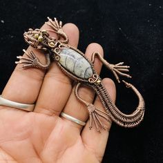 a hand holding a small lizard brooch in it's palm