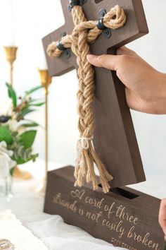 a person holding a wooden cross on top of a table