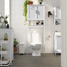 a white toilet sitting inside of a bathroom next to a plant filled wall above it