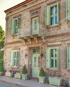 an old brick building with green shutters on the windows and balconies in front