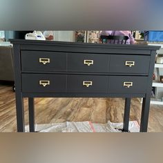 a black dresser with gold handles in a store display area next to a wooden floor