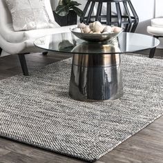 a living room with white chairs and a glass coffee table on top of a rug