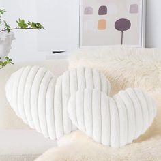 a white couch with pillows on top of it next to a potted plant in the corner