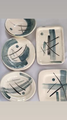 four plates with abstract designs on them sitting on top of a white tablecloth covered table