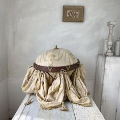 a hat sitting on top of a wooden table next to a white cabinet and window