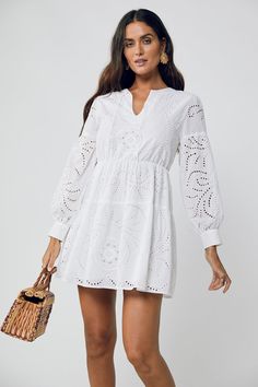 Dreamy summer staple. The June Ballon Sleeve Mini Dress screams summer vacay. Our White Broderie Anglaise 100% Cotton is light and effortless. With a lightly elasticated waist, loose fitting cuff sleeves this Aline Mini is featuring a V neck is fully lined and perfect for casual dinner on those balmy nights relaxing o Bohemian V-neck Crochet Dress For Day Out, Casual Crochet Dress With Pointelle Knit And V-neck, Beach Midi Length Dresses With Hollow Out, Beach Midi Length Dresses With Hollow Out Detail, Spring Maxi Length Dresses With Hollow Out, Chic Hollow Out Maxi Dress For Spring, Bohemian White Maxi Dress With Hollow-out Details, Spring Maxi Length Dress With Hollow Out Details, Chic Spring Maxi Dress With Hollow Out Details