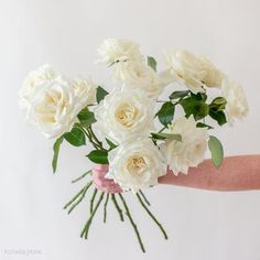 a person holding a bouquet of white roses in their hand with the stems still attached