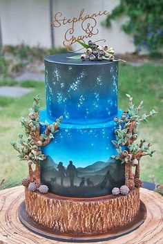 a three tiered cake decorated with blue and green frosting, stars and trees