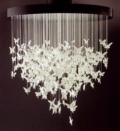 a chandelier with butterflies hanging from it's sides in a dark room