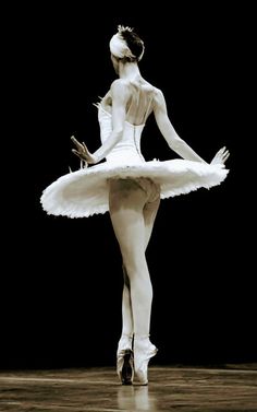 a ballerina in white is standing on the floor