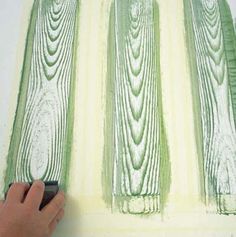 a person is using a brush to paint wood planks with green and yellow colors