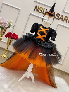 a dress made out of tulle and black, orange and white material with a witch's hat on top