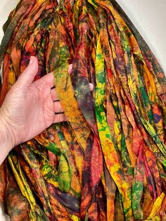 a person's hand reaching for a colorful piece of cloth