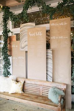 a wooden bench sitting in front of a wall with seating signs hanging from it's sides