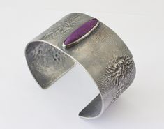 A very nice handmade cuff formed from 18 gauge Reticulation Silver.  The cuff is highlighted with a really nice Sugilite Gemstone.  The surface of the cuff has been oxidized and the oxidation partially removed to bring out the organic, dendritic nature of the surface. The cuff has an internal circumference of 7 inches which includes the gap of 1 inch. The bracelet is 1.3 inch wide. This would be a standard size bracelet that can be adjusted a bit. The Sugilite gemstone is natural and untreated. Mens Silver Cuff Bracelet, Gold Moonstone Ring, Womens Cuff Bracelets, Cuff Bracelets Handmade, Mens Cuff, Wide Cuff Bracelets, Natural Stone Bracelets, Unisex Bracelets, Silver Cuff Bracelet