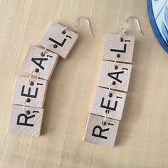 some type of earrings that are made out of scrabbles with the words real and real on them