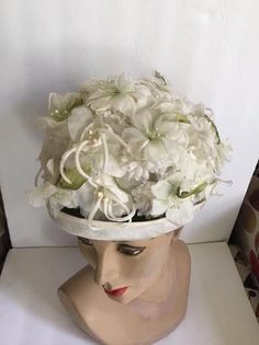 "Vintage 1960's hat. White floral with Green leaves bucket style hat. The label is *SEARS Fashion Millinery*. Sears Roebuck and Co. USA. *MORE INFORMATION BELOW* CONDITION: No issues noted. MEASURES: Inside circumference~21 1/2\" Height~5\" Front to back~8\" Left to right~7\" *WE APOLOGIZE~BUT WE NO LONGER SHIP TO GERMANY, ITALY OR SPAIN. IF ORDERS COME IN FROM GERMANY, ITALY OR SPAIN, WE WILL HAVE TO CANCEL THEM AND REFUND YOUR MONEY. SORRY FOR THIS INCONVENIENCE*" Vintage White Cloche Hat, Vintage Cream Mini Hats With Curved Brim, White Vintage Cloche Fascinator, Vintage Cream Mini Hat With Curved Brim, Vintage White Cloche Fascinator, Vintage Cream Costume Hat With Curved Brim, Vintage White Fascinator Hat, White Vintage Fascinator Hat, Vintage White Fascinator With Curved Brim