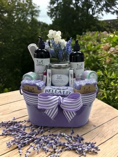 the lavender spa gift basket is sitting on a wooden table with lavenders around it