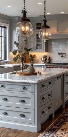 a large kitchen island with lights hanging from it's ceiling and an area rug on the floor