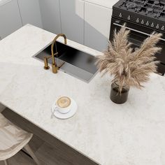 a white counter top with a coffee cup and saucer on it next to a stove